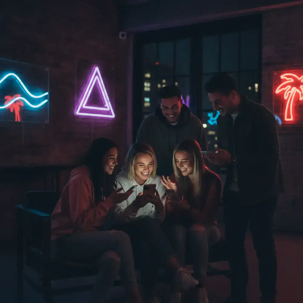 Friends smiling and playing on mobile devices
